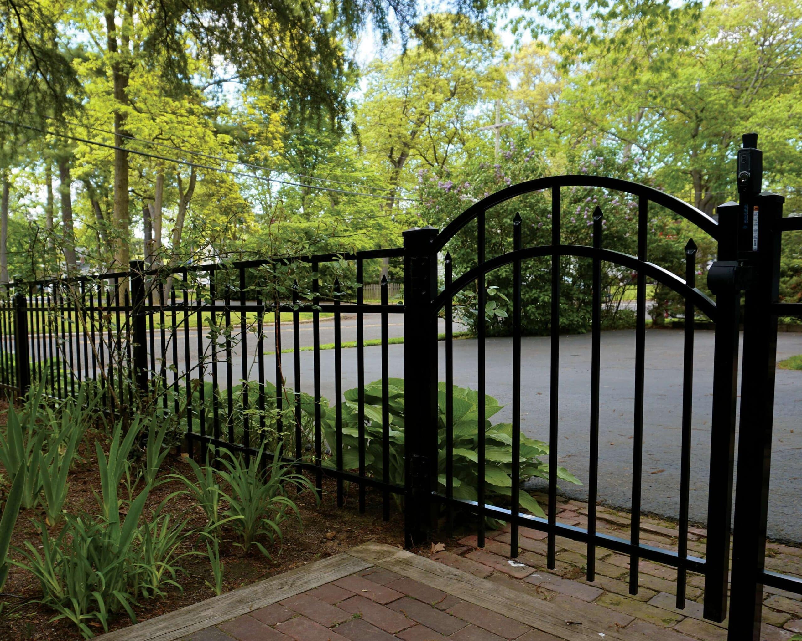 A gated entrance to a driveway, with the driveway just behind an Active Yards Amethyst aluminum fence with Arched Gate
